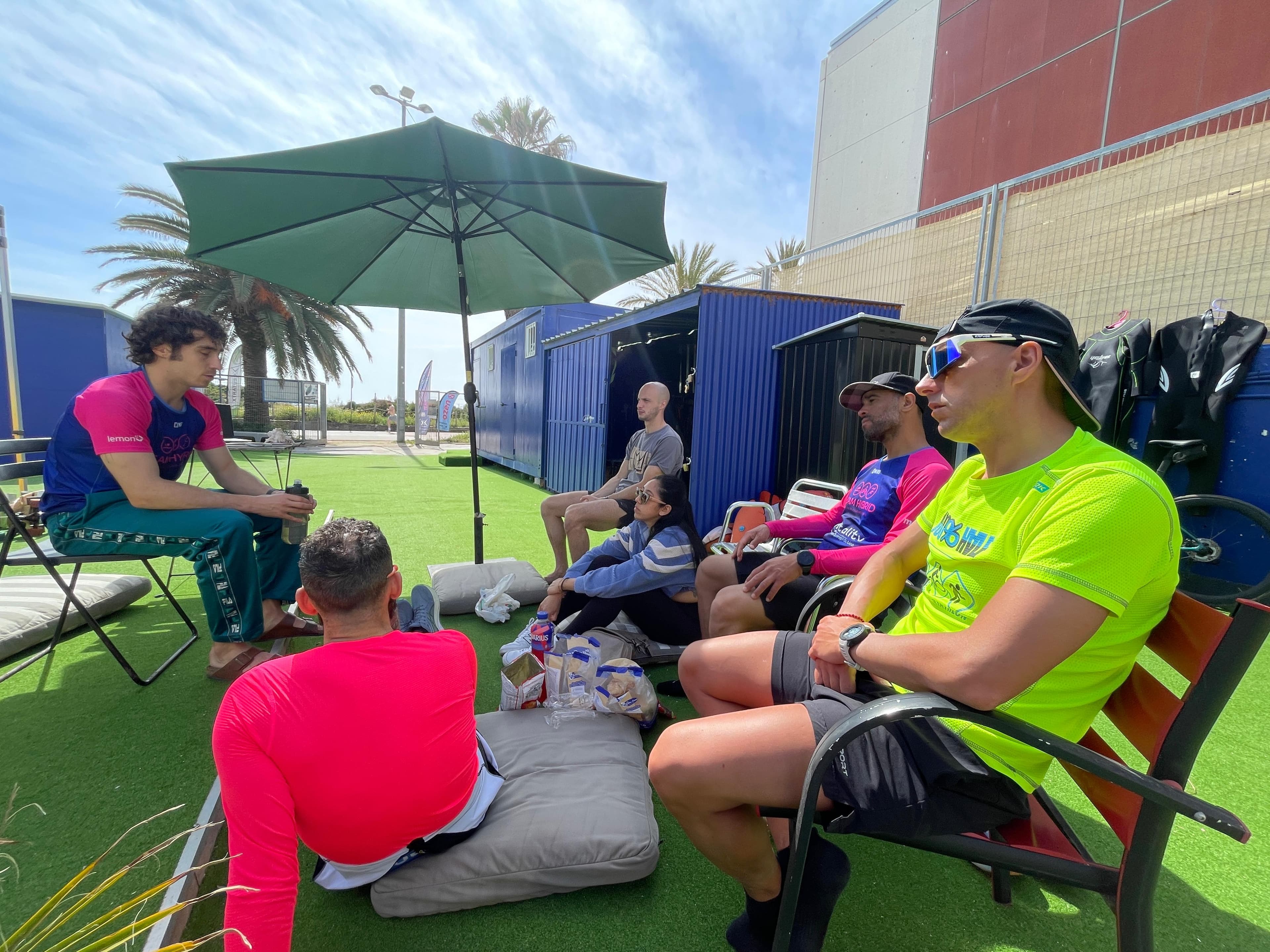 Athletes gathered on the turf under a green umbrella